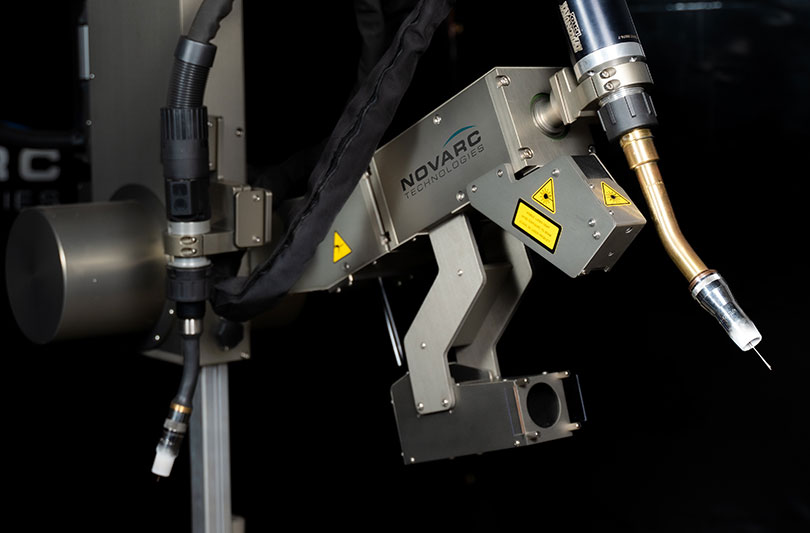 A close-up of industrial robotic welding equipment with a metallic arm, featuring components labeled "Novarc Technologies."