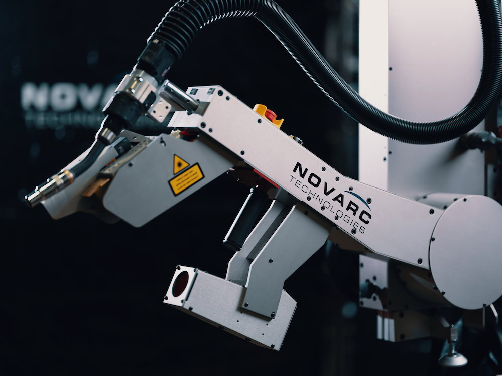 A close-up of a robotic arm from Novarc Technologies, equipped with a welding tool. The arm features a sleek design with visible controls and cables against a dark, blurred background.