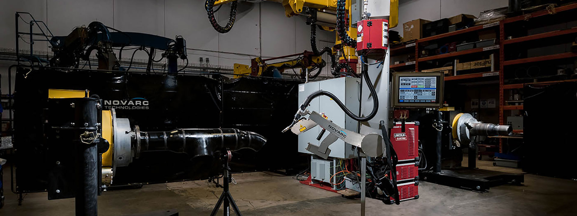 Industrial robot in a manufacturing setting, featuring machines and equipment with a computer screen displaying information.