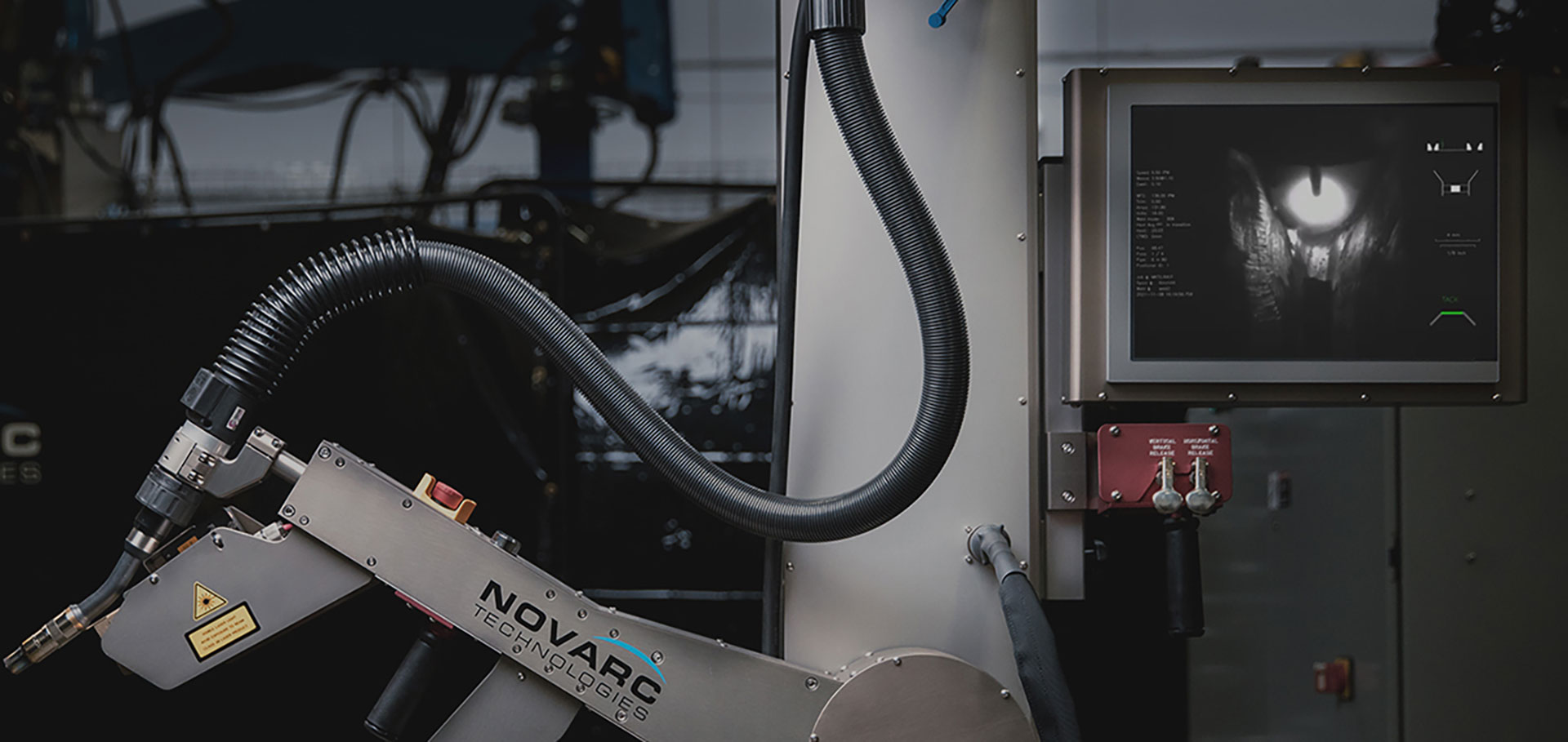 A robotic welding arm in a workshop, featuring a flexible tube arm and a control panel displaying a welding process. The equipment is branded with "Novarc Technologies.